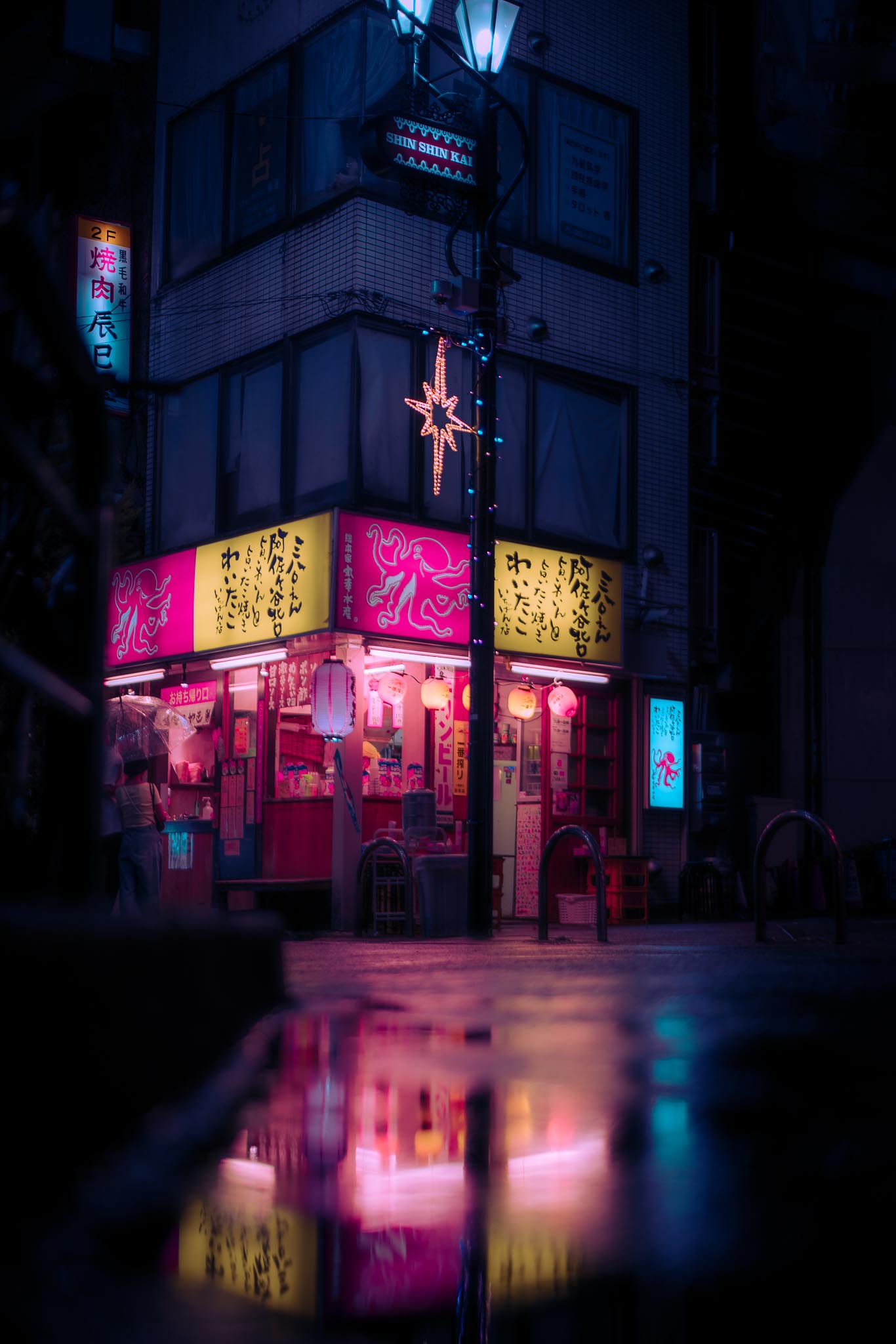 Asagaya Tokyo at night — pink takoyaki shop corner reflecting in rain puddle