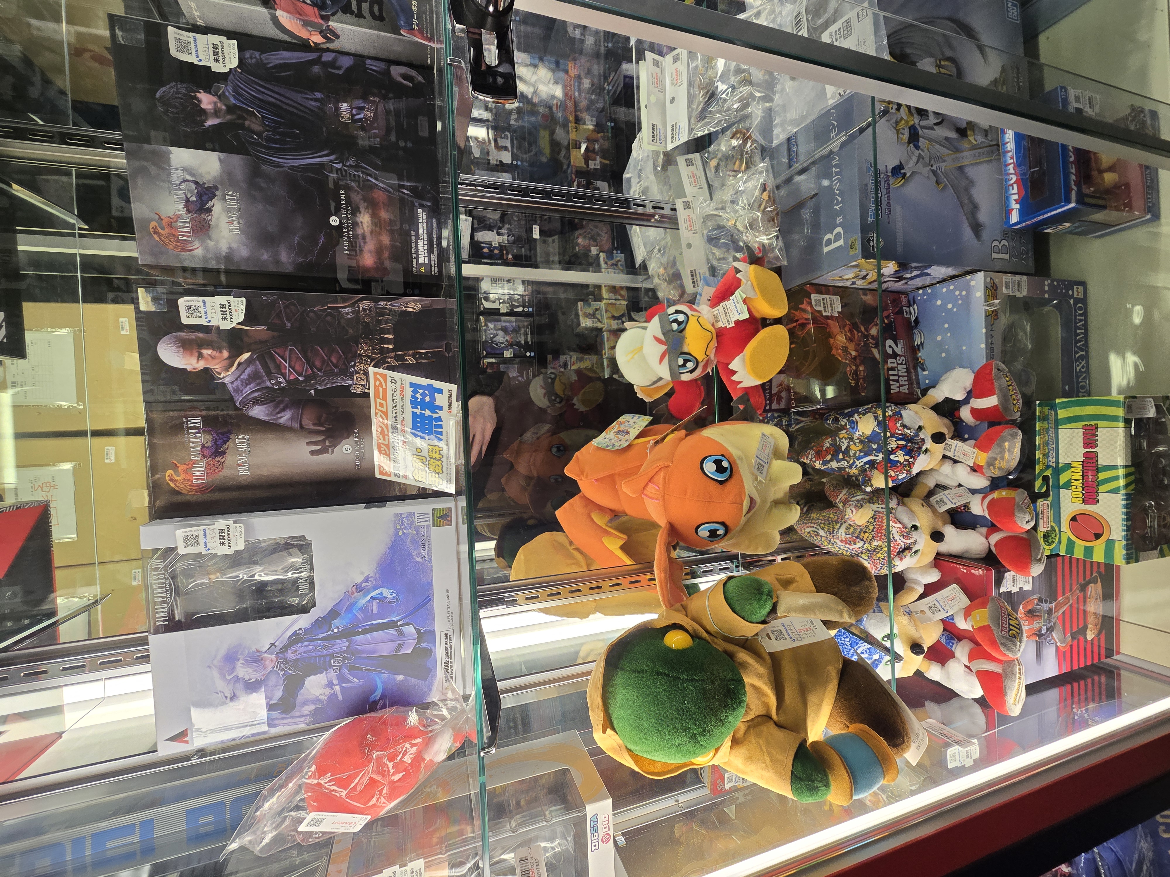 Glass display case with Digimon plushies and Resident Evil figures at Mikado Ikebukuro