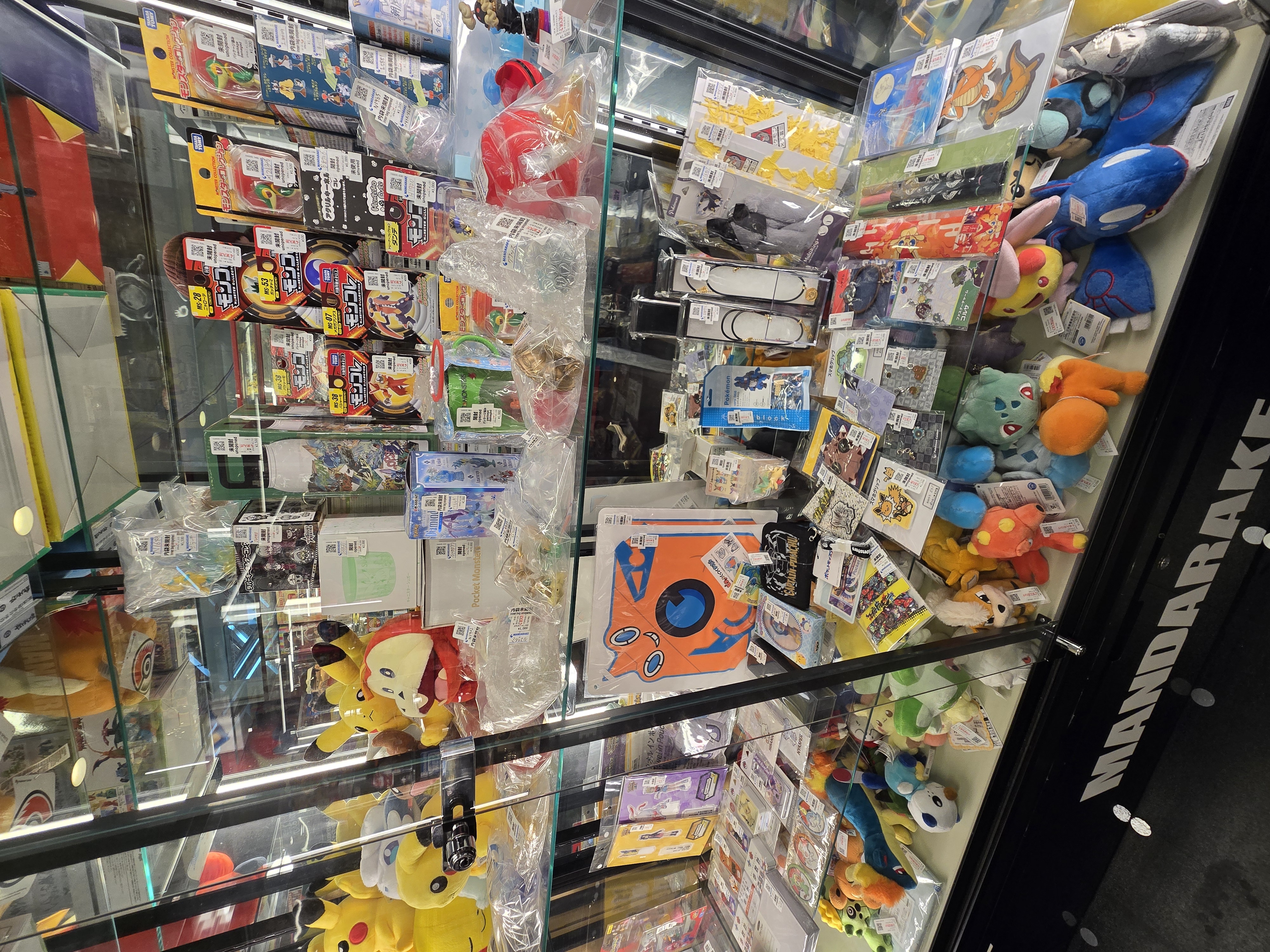 Glass display case packed with Pokemon and anime figures at Mikado Ikebukuro — Mandarake