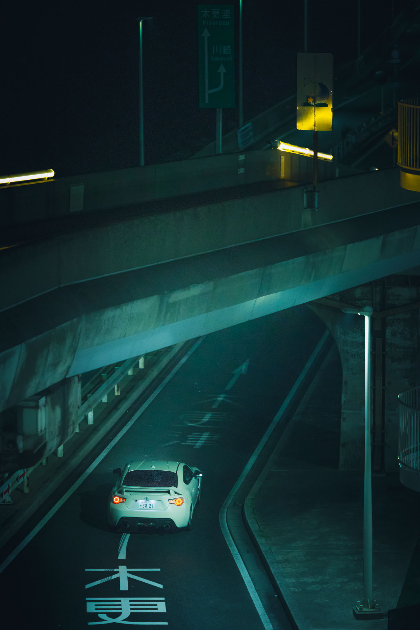 White Toyota 86 driving under elevated highway at night toward Kawasaki — Aqua-Line approach