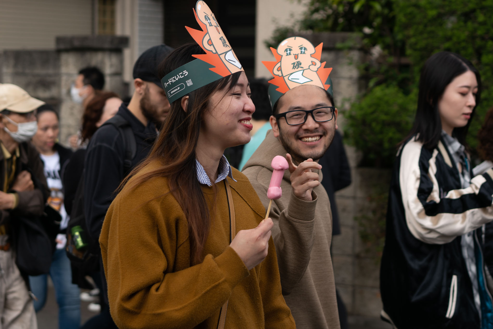 Kanamara Matsuri crowd — couple with paper hats and festival souvenir Kawasaki