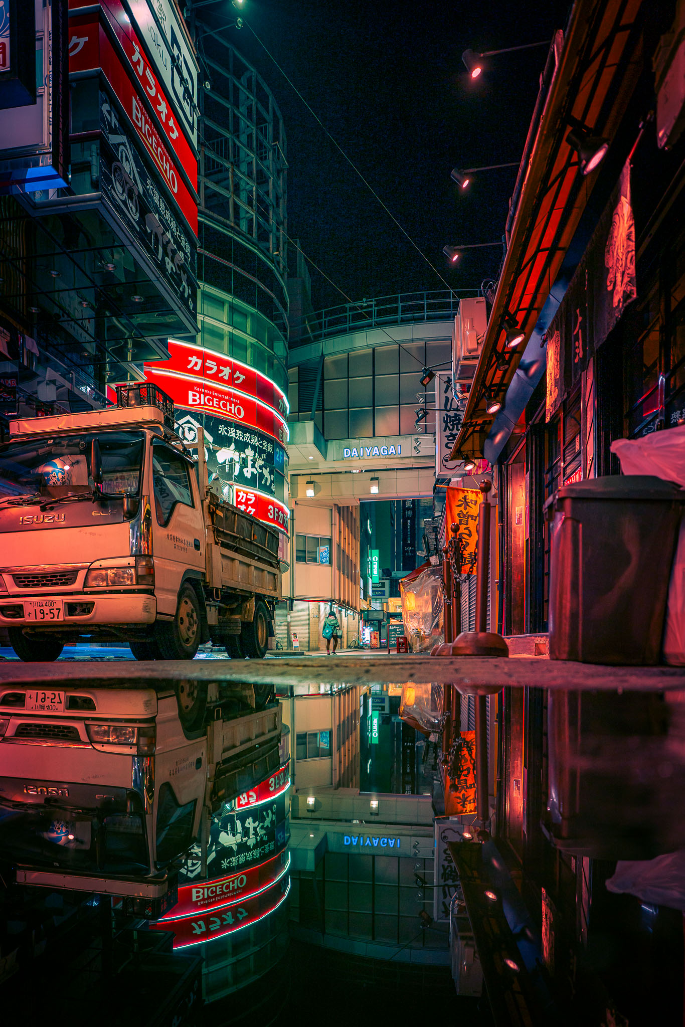 Wet street reflection of neon signs and a parked truck at the Diamond Street arcade entrance in Kichijoji, Tokyo