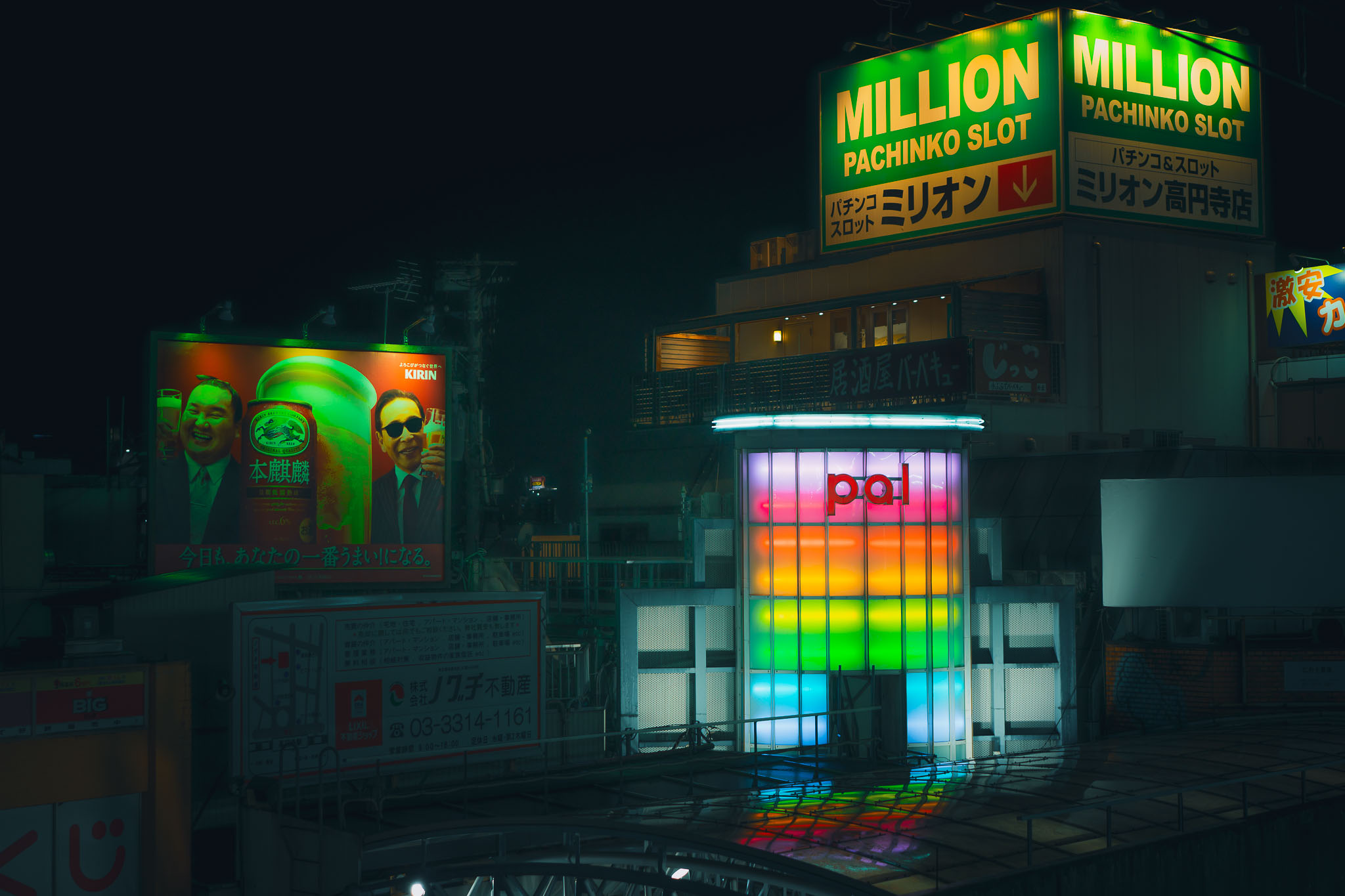 Rainbow-lit glass entrance to Pal Shopping Street in Koenji, Tokyo, beneath a giant green Million Pachinko Slot sign