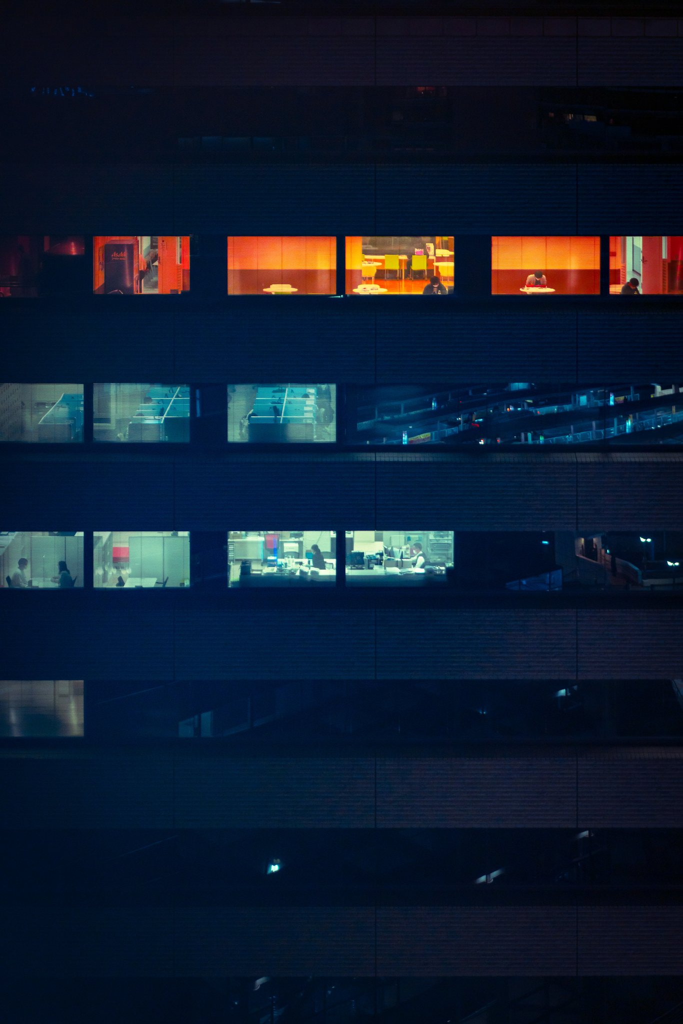 Tokyo office buildings lit up at night — city skyline from below