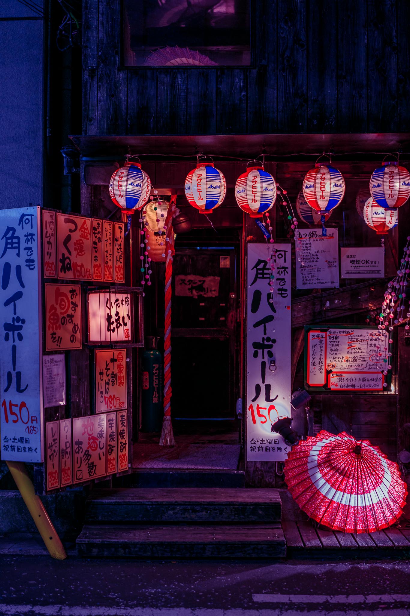 Izakaya entrance with red and white paper lanterns and a wagasa umbrella — Mizonokuchi at night