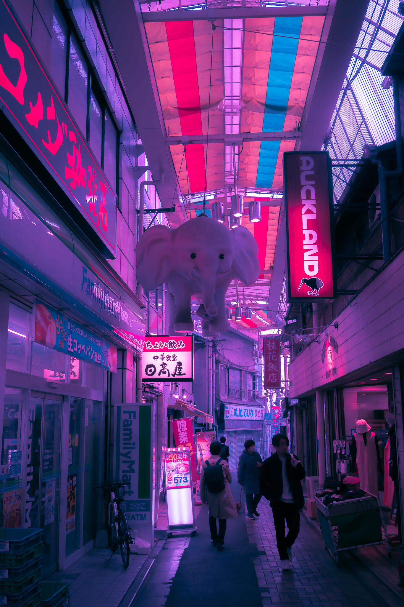Ogikubo Sun Road covered arcade at night — white elephant sculpture and neon signs