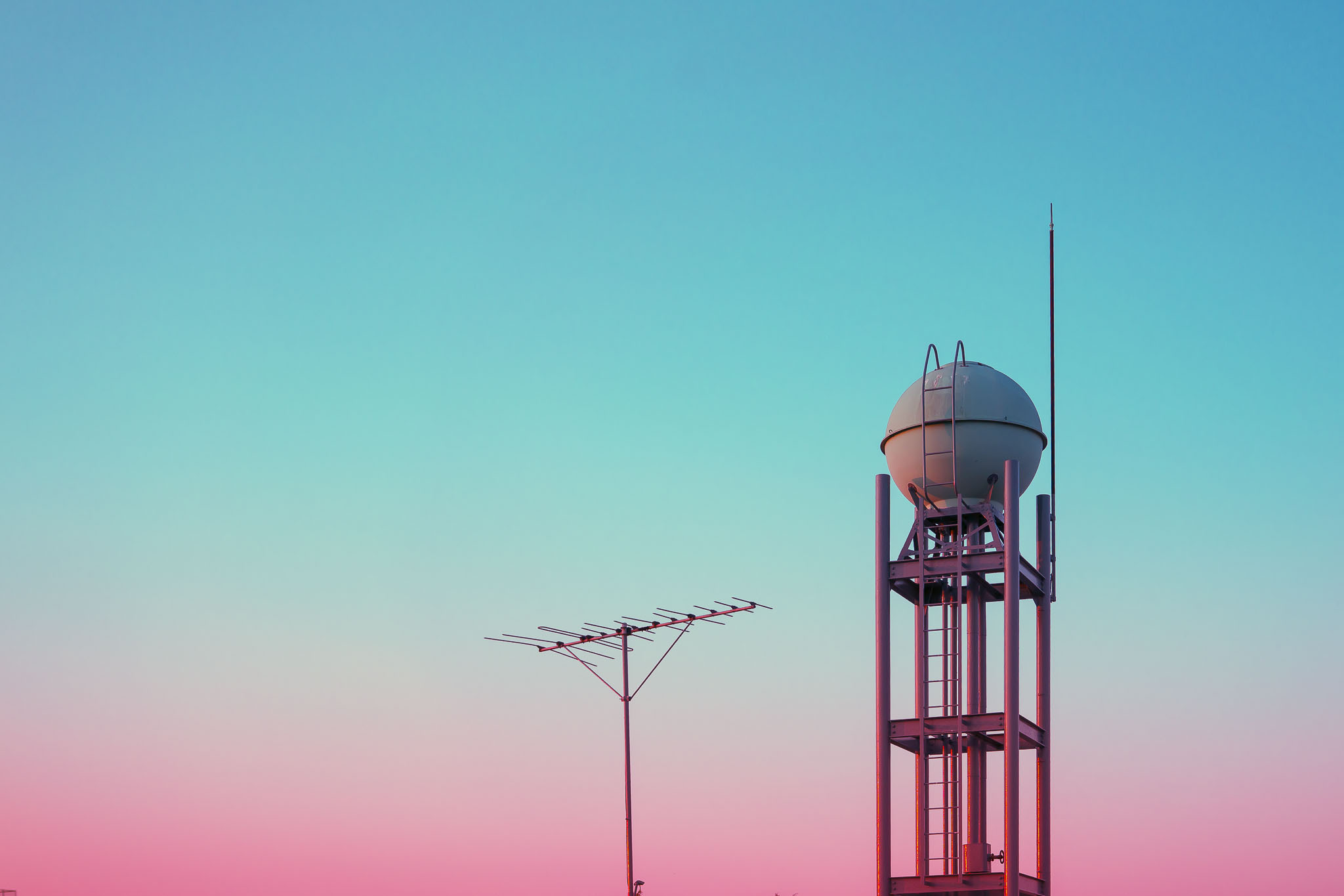 Water tower and TV antenna against teal to pink gradient sky in Ogikubo Tokyo
