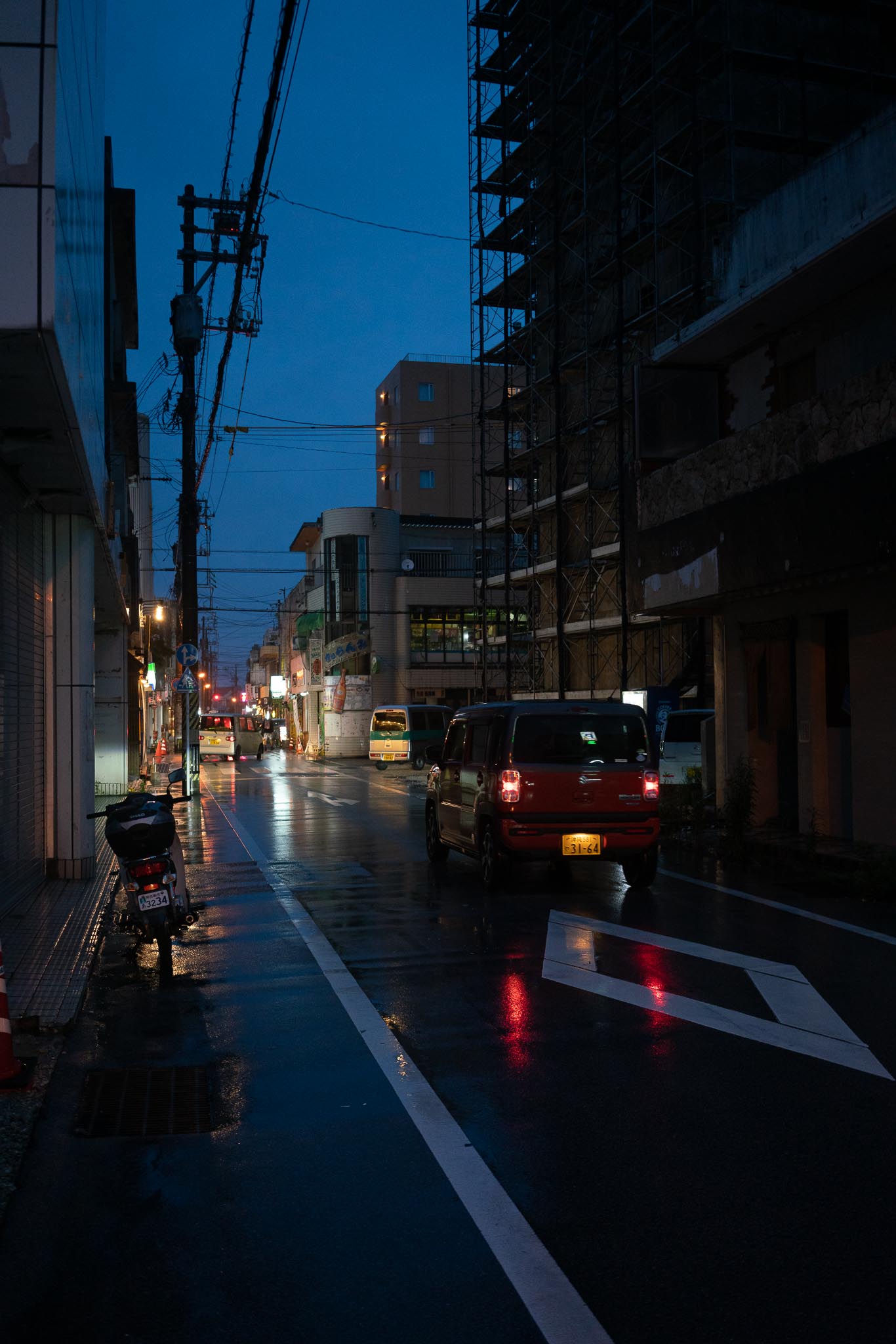 Blue hour rainy street in Okinawa — red car and wet road reflections at night