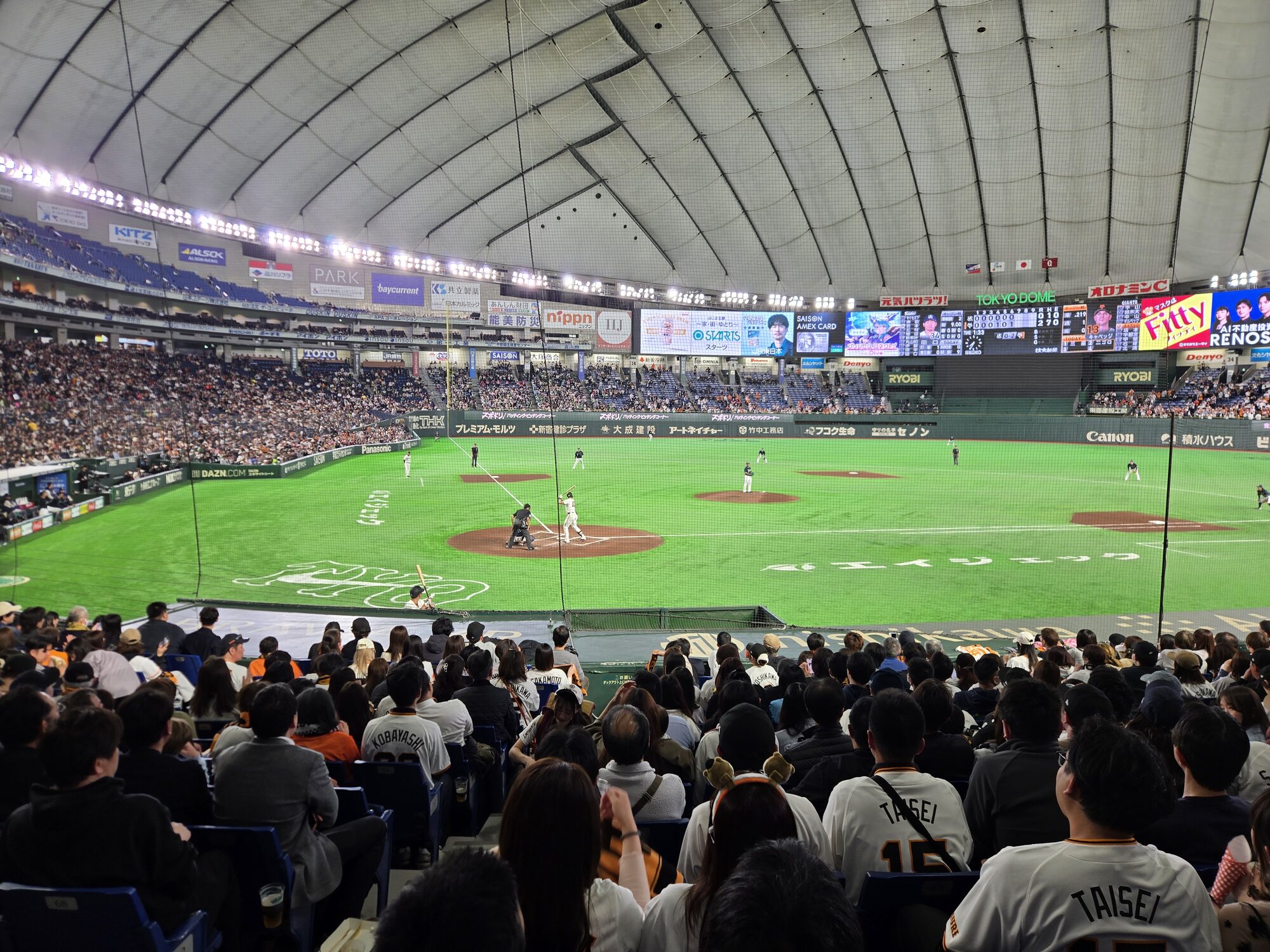 Yomiuri Giants game at Tokyo Dome — wide shot of the field from the stands, crowd in foreground